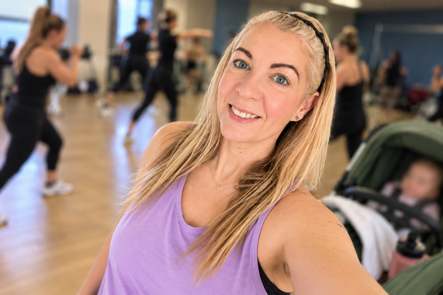 Saffron returning to a Body Combat class after having a baby, with a blurred baby in a green pushchair behind her.