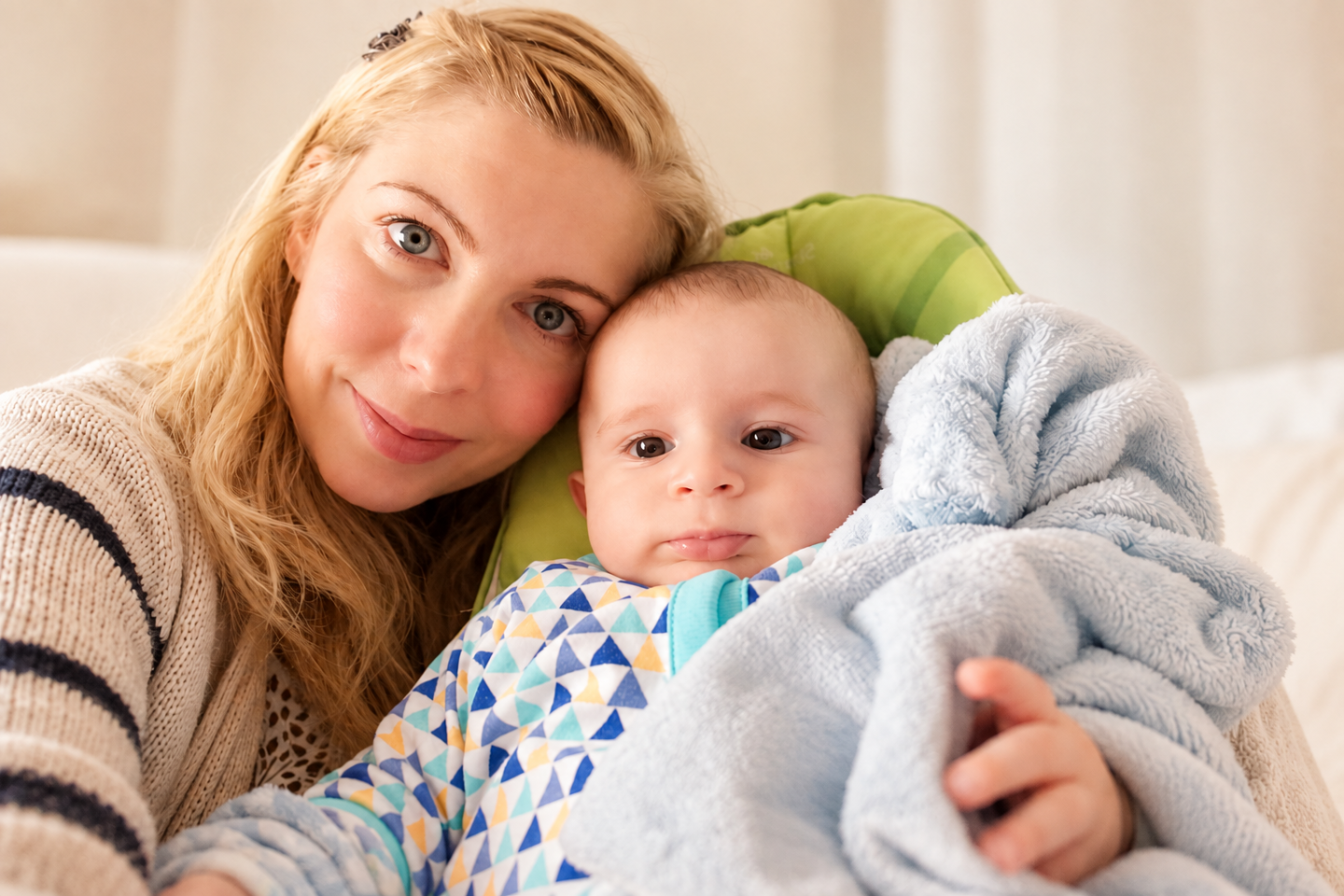 Saffron cuddling baby Cyrus during maternity leave at 40, wrapped in a soft blue blanket at home.