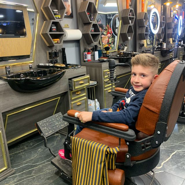 A boy getting his hair cut in the barber shop