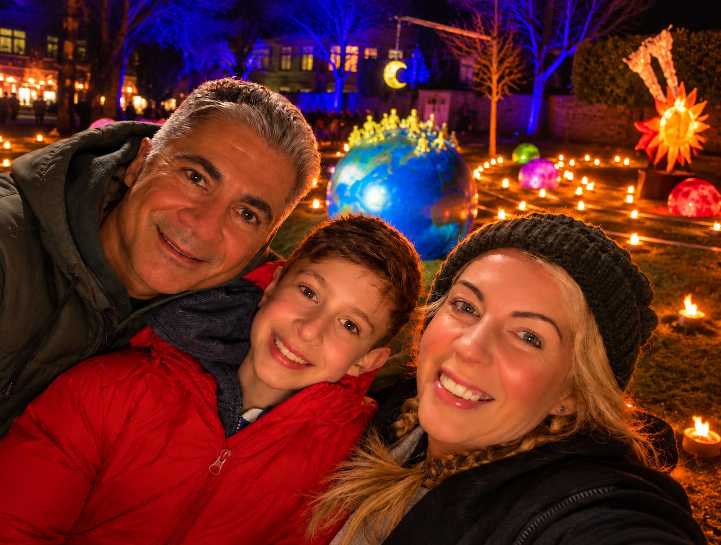 Family selfie together in front of glowing outdoor fires during a winter light event.