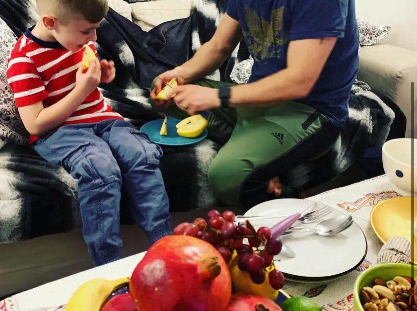 A boy and a man eating fruit for Shab e Yalda